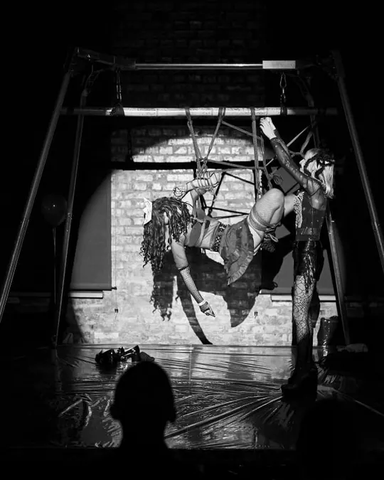 A rope suspension in a spotlight on a dark stage lined with candles.
